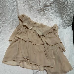 A tan blouse with ruffles and a seamless print on the top.